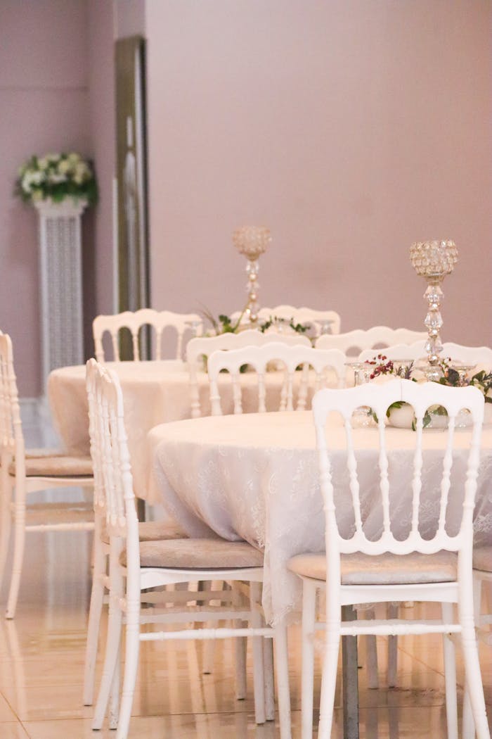 Chic banquet hall with white chairs, round tables, and candelabras, perfect for elegant events.
